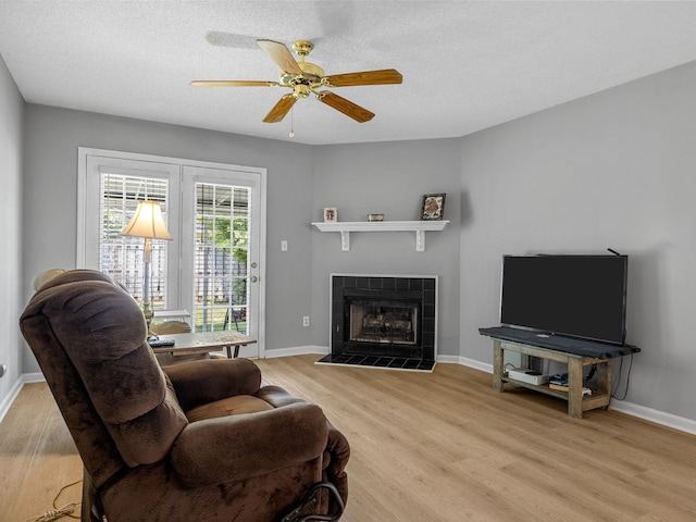 1156 Webber, Spartanburg, SC 29307 - living area featuring light wood finished floors, a tiled fireplace, a ceiling fan, baseboards, and a textured ceiling
