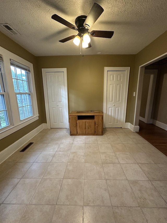 221 Mill, Gaffney, SC 29341 - unfurnished bedroom featuring a textured ceiling, light tile patterned floors, baseboards, ceiling fan, and two closets
