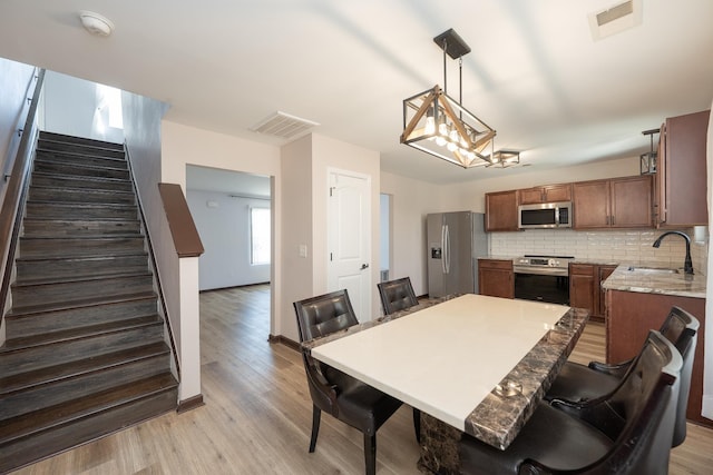 170 Old Timber, Woodruff, SC 29388 - kitchen featuring appliances with stainless steel finishes, a sink, light wood finished floors, a breakfast bar, and tasteful backsplash
