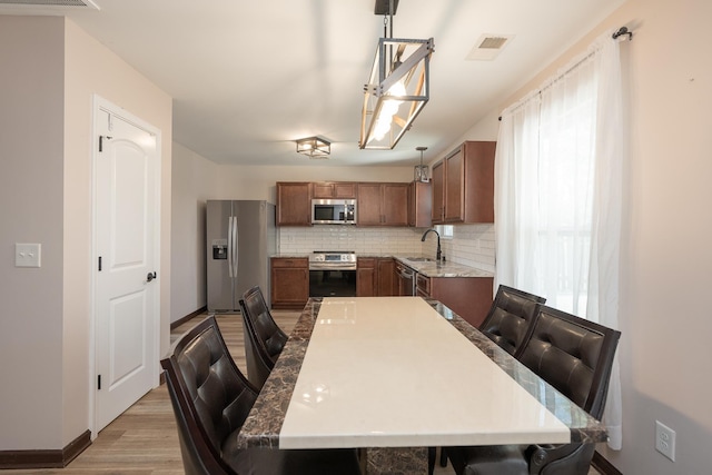 170 Old Timber, Woodruff, SC 29388 - kitchen featuring stainless steel appliances, a sink, light wood-style flooring, decorative backsplash, and baseboards
