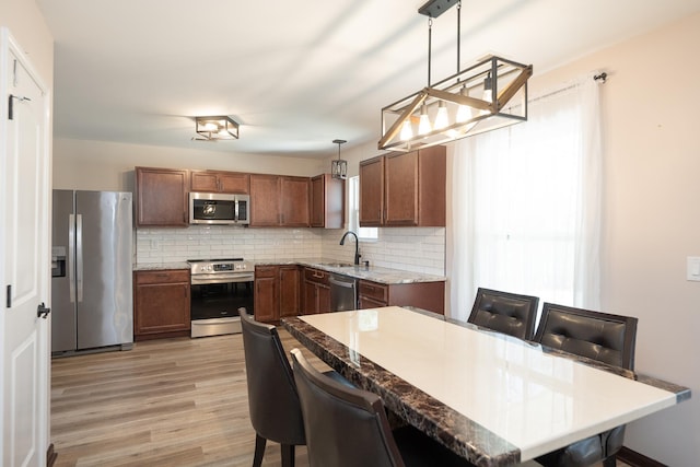 170 Old Timber, Woodruff, SC 29388 - kitchen featuring stainless steel appliances, a sink, decorative backsplash, light wood-type flooring, and hanging light fixtures