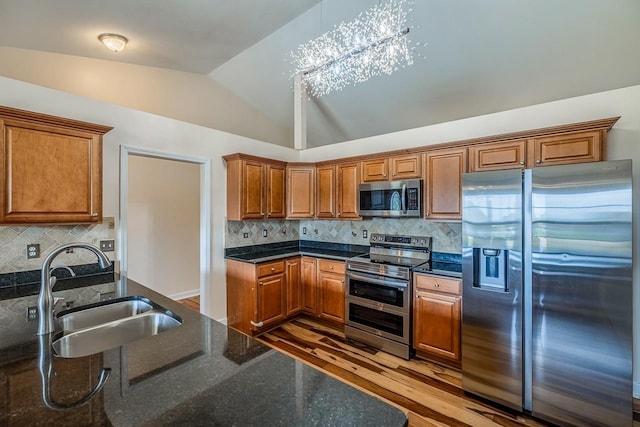 217 Legacy, Inman, SC 29349 - kitchen featuring appliances with stainless steel finishes, a sink, vaulted ceiling, brown cabinetry, and wood finished floors