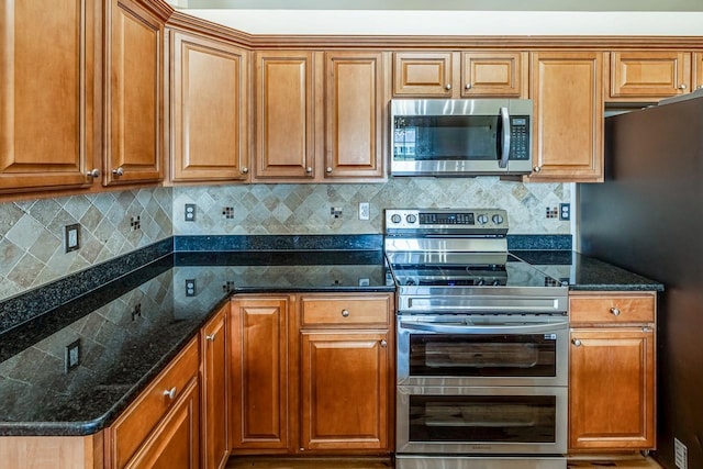 217 Legacy, Inman, SC 29349 - kitchen featuring stainless steel appliances, tasteful backsplash, dark stone counters, and brown cabinets