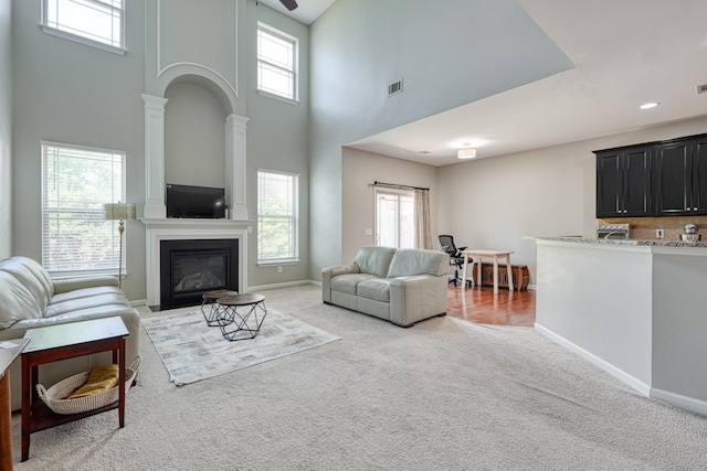 514 Millervale, Greer, SC 29650 - living area featuring a high ceiling, light colored carpet, plenty of natural light, a glass covered fireplace, and baseboards