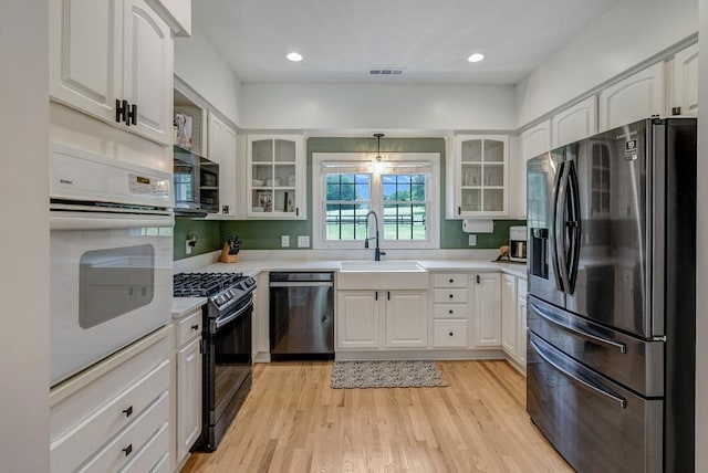 355 Night Lark, Campobello, SC 29322 - kitchen featuring appliances with stainless steel finishes, a sink, light countertops, white cabinets, and glass insert cabinets