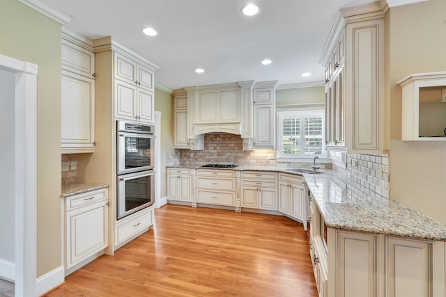 121 Commons, Spartanburg, SC 29302 - kitchen with double oven, light wood finished floors, backsplash, recessed lighting, and light stone counters