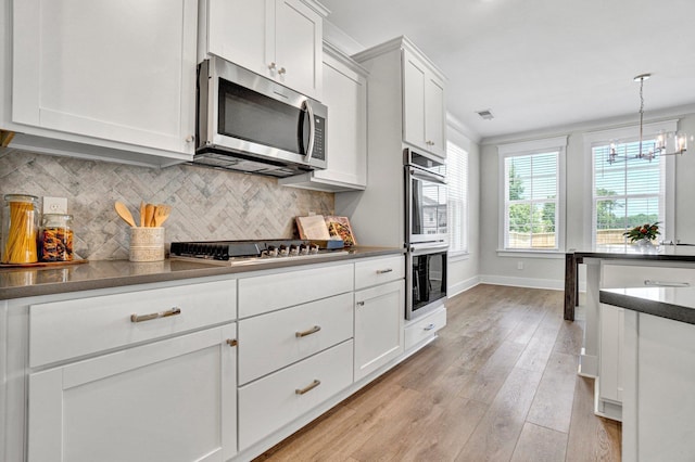 206 Hoss, Greenville, SC 29615 - kitchen featuring appliances with stainless steel finishes, dark countertops, a chandelier, tasteful backsplash, and light wood-type flooring