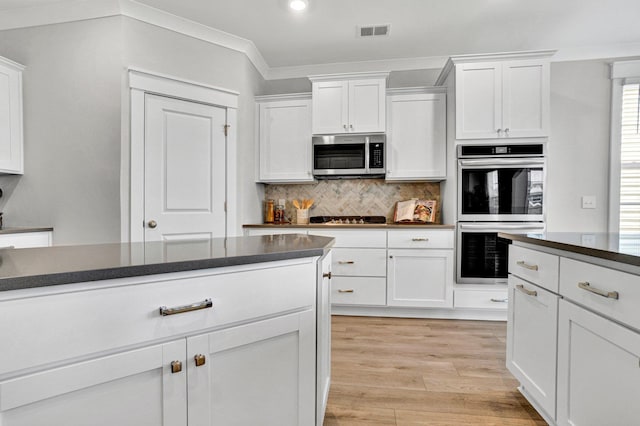 206 Hoss, Greenville, SC 29615 - kitchen featuring stainless steel microwave, double wall oven, dark countertops, white cabinetry, and crown molding