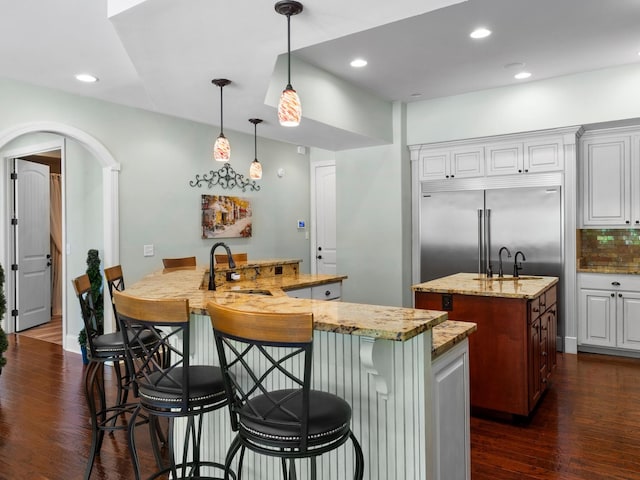 220 Fincher, Pauline, SC 29374 - kitchen featuring a kitchen island with sink, built in refrigerator, a sink, dark wood-style floors, and light stone counters