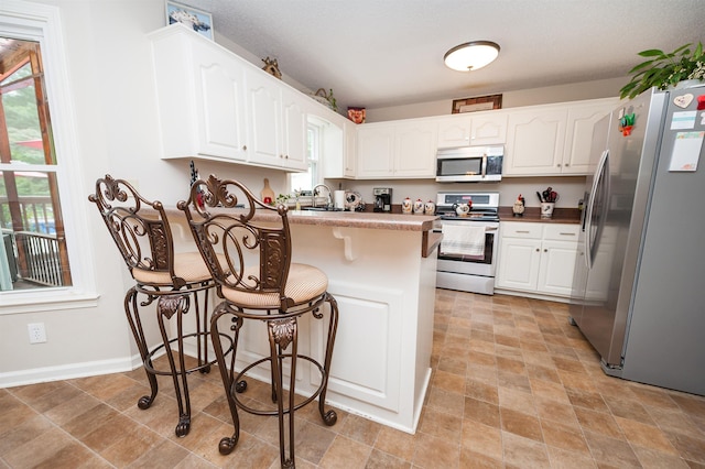 477 Cresthaven, Boiling Springs, SC 29316 - kitchen with stainless steel appliances, a peninsula, white cabinets, a kitchen breakfast bar, and baseboards