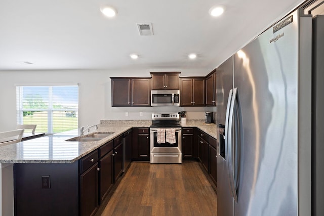 259 Millen, Woodruff, SC 29388 - kitchen featuring appliances with stainless steel finishes, dark wood-type flooring, dark brown cabinets, a peninsula, and light stone counters
