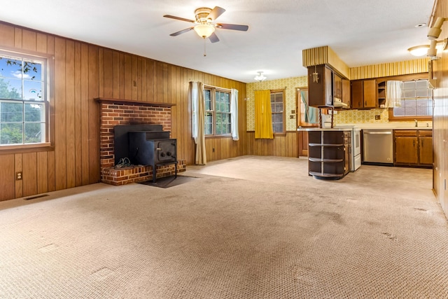 207 Oakmont Dr, Spartanburg, SC 29316 - unfurnished living room with a wood stove, ceiling fan, light carpet, and wooden walls