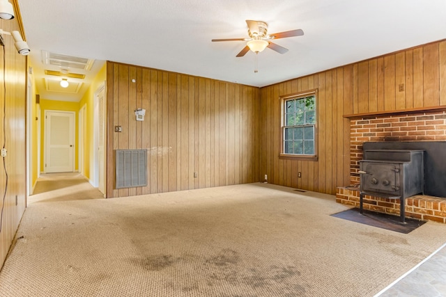 207 Oakmont Dr, Spartanburg, SC 29316 - unfurnished living room with a wood stove, ceiling fan, wood walls, and carpet flooring