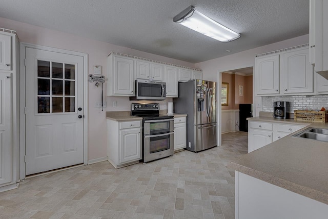 409 Cresthaven, Boiling Springs, SC 29316 - kitchen featuring stainless steel appliances, white cabinets, a textured ceiling, tasteful backsplash, and light countertops