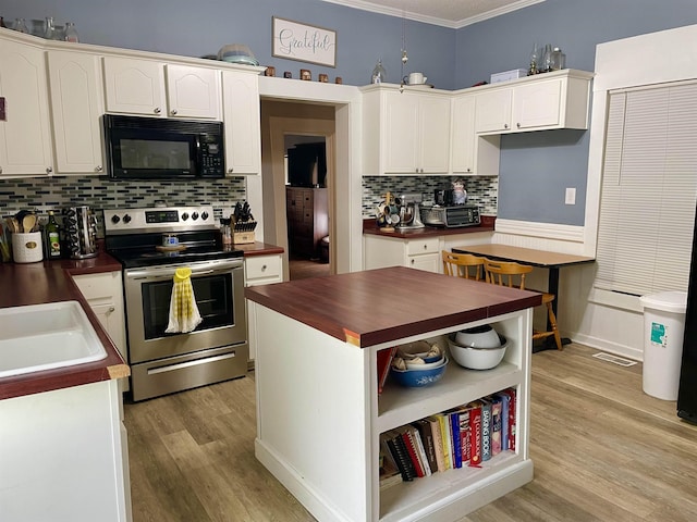 511 El Bethel Rd, Gaffney, SC 29340 - kitchen featuring black microwave, stainless steel electric range oven, butcher block counters, ornamental molding, and light wood-type flooring