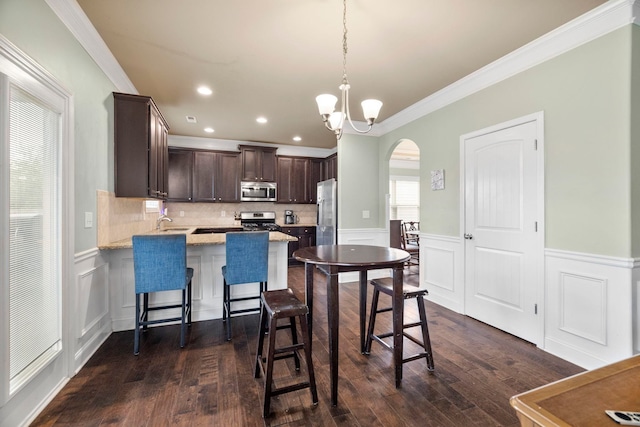 415 Bridge Xing, Simpsonville, SC 29681 - kitchen with appliances with stainless steel finishes, arched walkways, dark brown cabinetry, ornamental molding, and a peninsula