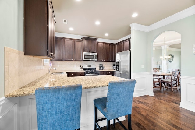 415 Bridge Xing, Simpsonville, SC 29681 - kitchen with stainless steel appliances, dark brown cabinets, ornamental molding, light stone counters, and a peninsula