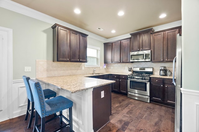 415 Bridge Xing, Simpsonville, SC 29681 - kitchen with stainless steel appliances, dark brown cabinets, a peninsula, ornamental molding, and dark wood-style flooring