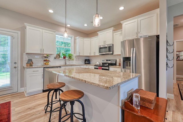 119 W Caylee, Chesnee, SC 29323 - kitchen with appliances with stainless steel finishes, white cabinetry, decorative backsplash, light wood finished floors, and a center island