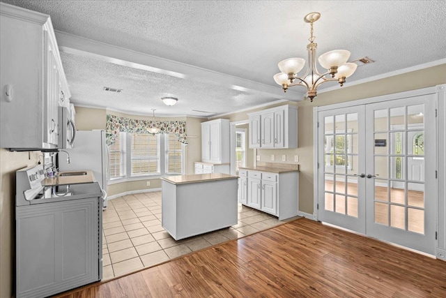 298 Askew, Union, SC 29379 - kitchen with electric range, a textured ceiling, stainless steel microwave, a chandelier, and a kitchen island