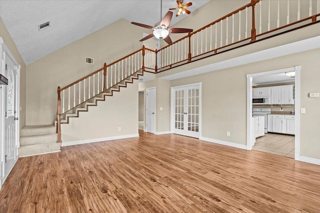 298 Askew, Union, SC 29379 - unfurnished living room with high vaulted ceiling, light wood-style flooring, a ceiling fan, french doors, and stairway