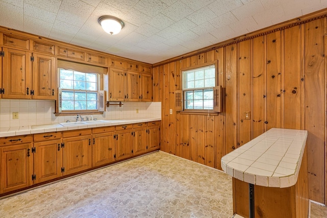 104 Pine, Laurens, SC 29360 - kitchen with healthy amount of natural light, brown cabinets, backsplash, tile countertops, and wood walls