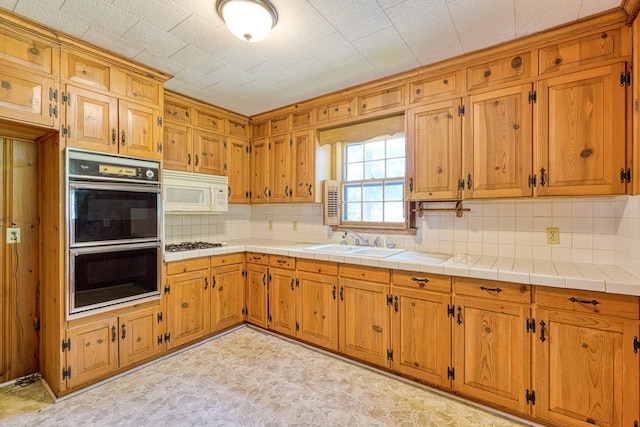104 Pine, Laurens, SC 29360 - kitchen featuring double oven, white microwave, gas stovetop, decorative backsplash, and brown cabinetry