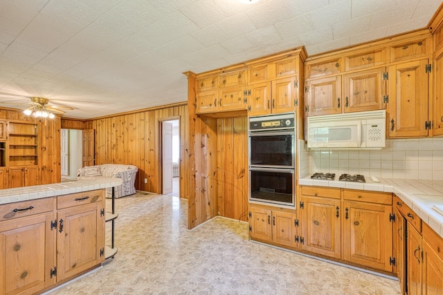 104 Pine, Laurens, SC 29360 - kitchen with white appliances, tile counters, backsplash, wooden walls, and ceiling fan