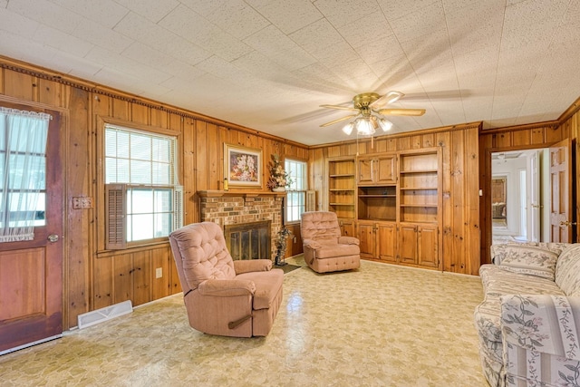 104 Pine, Laurens, SC 29360 - living area featuring wooden walls, plenty of natural light, a brick fireplace, a ceiling fan, and ornamental molding