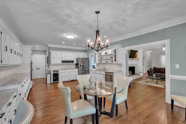 207 Carolina Club Dr, Spartanburg, SC 29306 - dining space featuring a chandelier, wood finished floors, crown molding, a fireplace with raised hearth, and recessed lighting