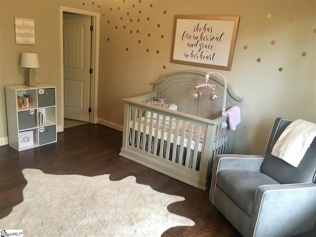 bedroom with dark wood-type flooring and a nursery area