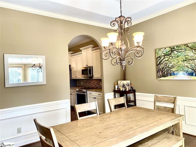 dining space featuring crown molding, dark wood-type flooring, and a chandelier