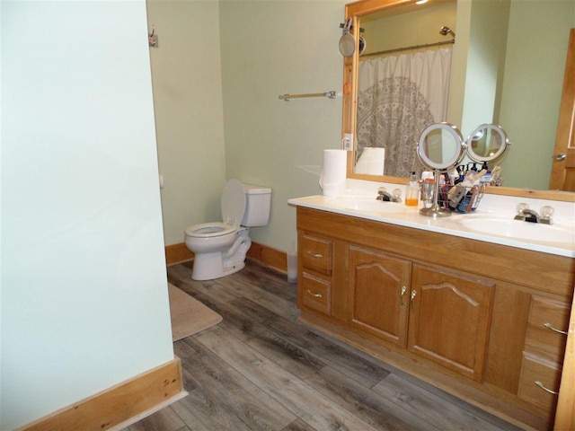 bathroom with hardwood / wood-style floors, oversized vanity, toilet, and dual sinks