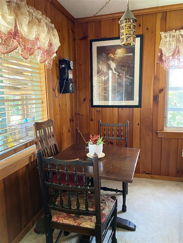 dining space with light carpet and wood walls