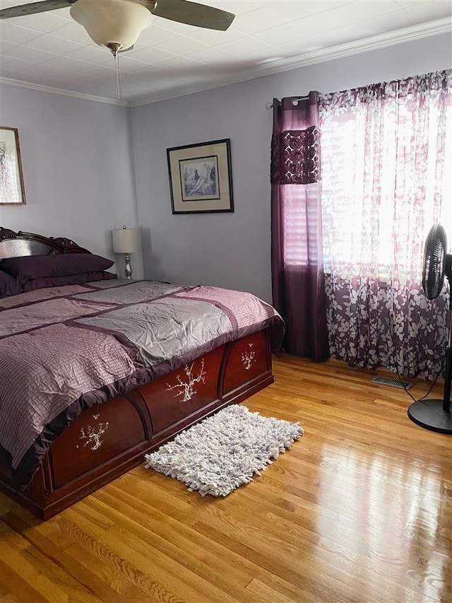 bedroom with ceiling fan, light wood-type flooring, and crown molding