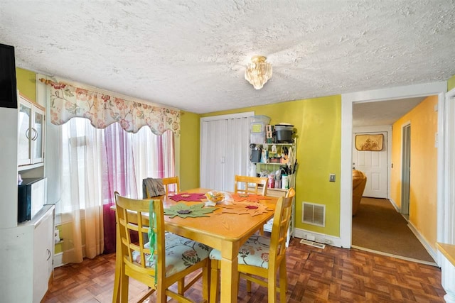 dining area featuring a textured ceiling and dark parquet flooring