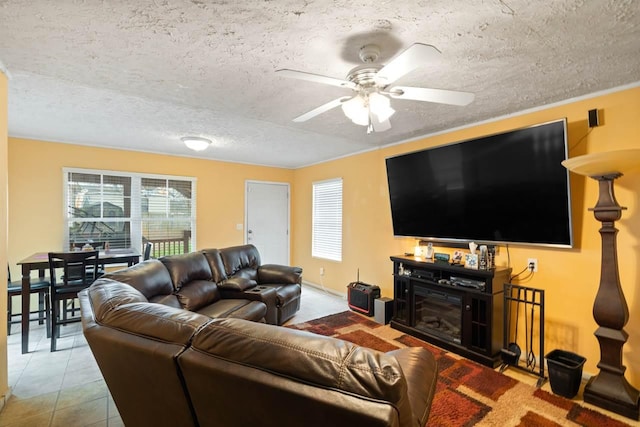 living room with ceiling fan, a textured ceiling, and light tile floors