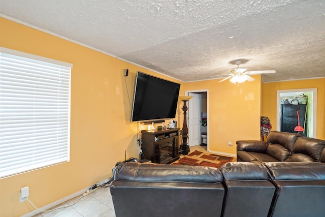 living room with ceiling fan, a healthy amount of sunlight, light tile floors, and a textured ceiling