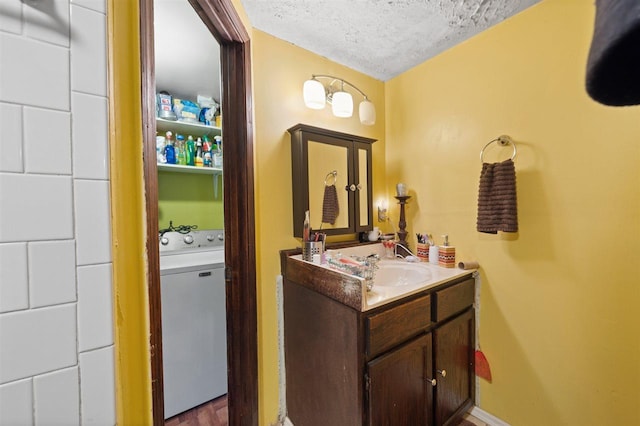 bathroom with washer / clothes dryer, a textured ceiling, hardwood / wood-style floors, and vanity with extensive cabinet space