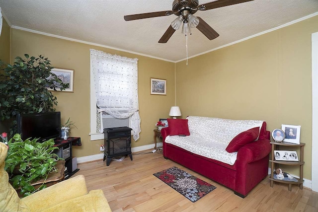 bedroom featuring ceiling fan, a wood stove, light hardwood / wood-style flooring, and a textured ceiling