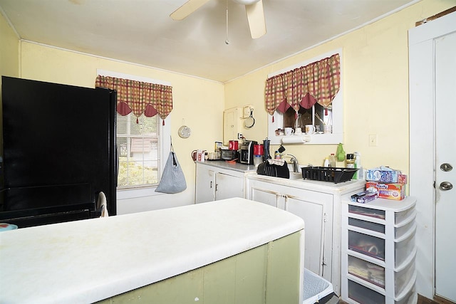 kitchen with white cabinets, ceiling fan, black fridge, and green cabinets