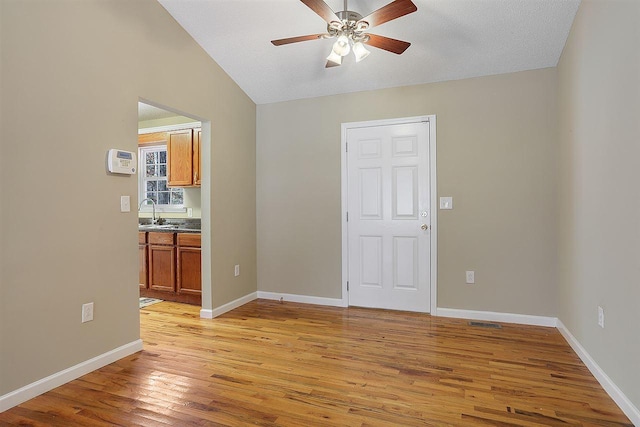 interior space with ceiling fan, sink, light hardwood / wood-style floors, and vaulted ceiling