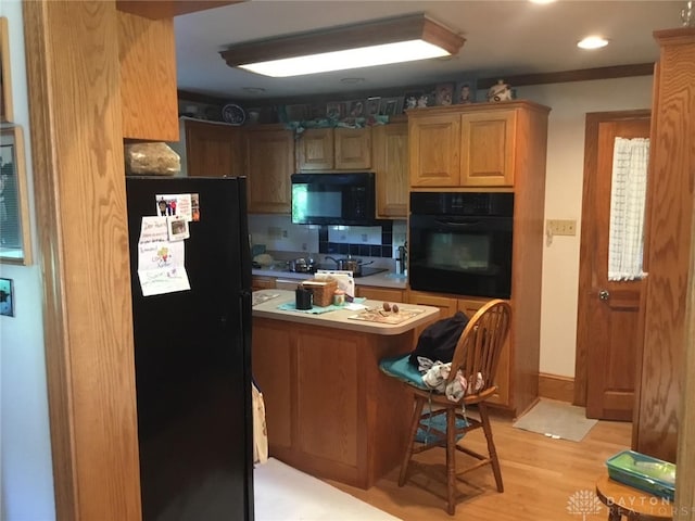 kitchen with backsplash, black appliances, and light hardwood / wood-style flooring