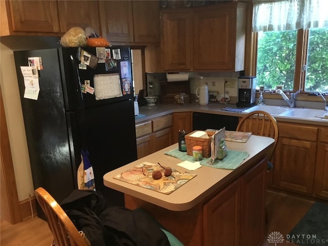 kitchen with sink, a breakfast bar area, black appliances, and light hardwood / wood-style floors