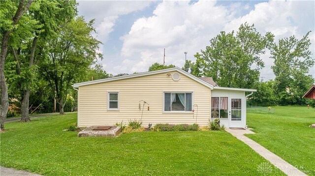 rear view of property featuring a yard and an outdoor fire pit