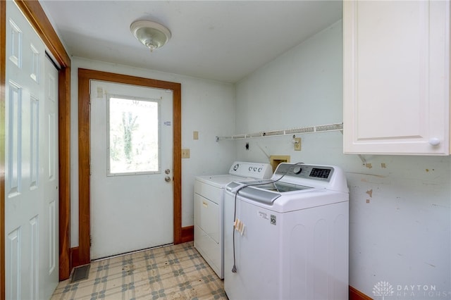 laundry area with cabinets, washing machine and dryer, and light tile patterned floors