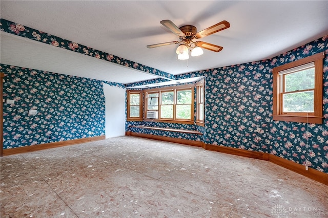 empty room featuring a wealth of natural light, ceiling fan, and cooling unit