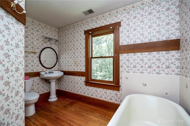 bathroom featuring a textured ceiling, toilet, wood-type flooring, and a bathtub