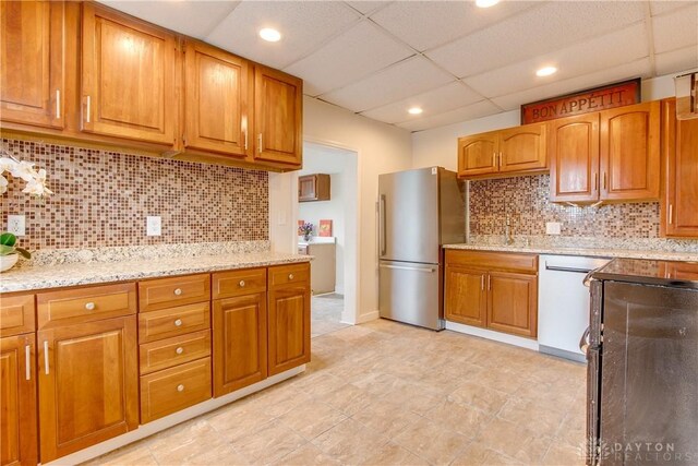216 S Short St, Troy, OH 45373 - kitchen with freestanding refrigerator, dishwasher, a drop ceiling, decorative backsplash, and brown cabinets