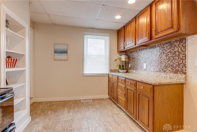 216 S Short St, Troy, OH 45373 - kitchen featuring brown cabinetry, backsplash, a drop ceiling, stainless steel range with electric cooktop, and light tile patterned floors